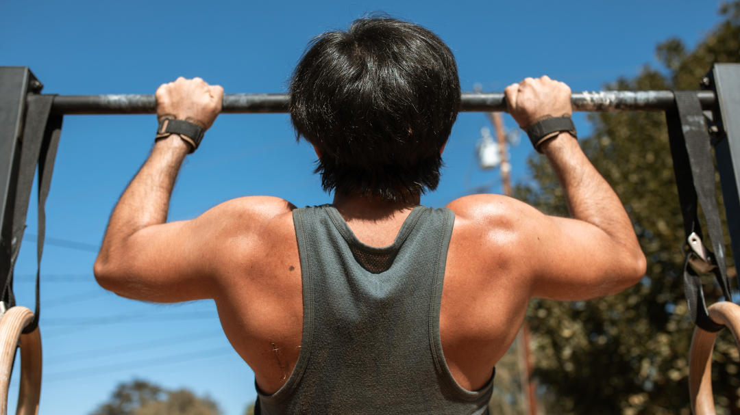 workout consistency leads to woman doing a pull up outside